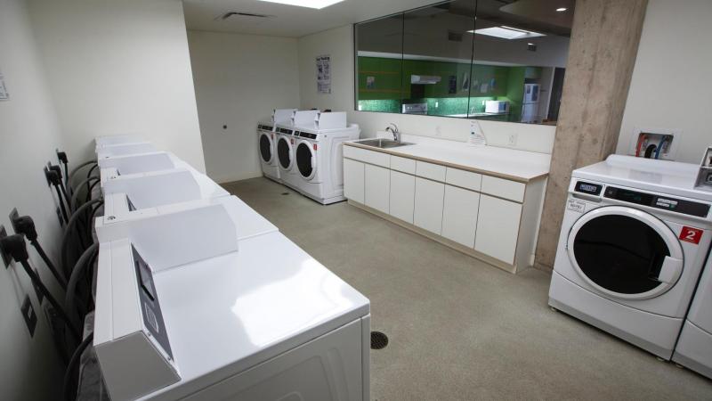 laundry room with washers and dryers along two walls and a long countertop with a sink