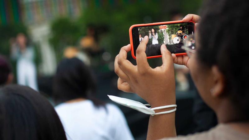 A student captures an image on a cell phone during an LUaroo performance.
