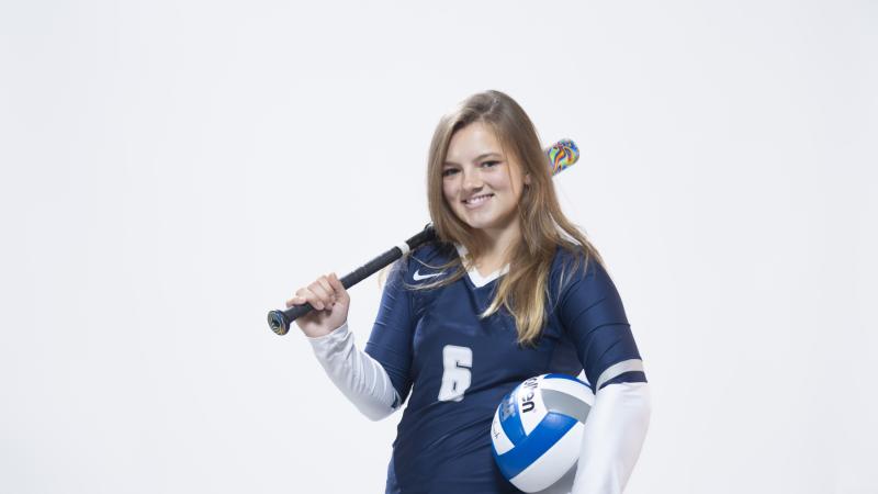 Taylor Hughes '25 holds a softball bat and volleyball during a Media Day photo shoot.